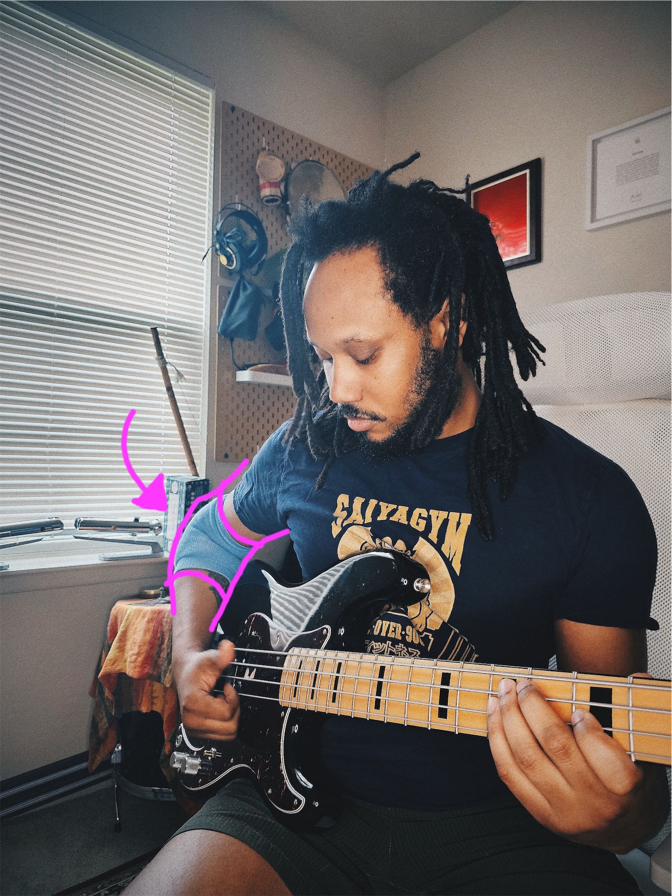 Annotate photo of me playing the bass while wearing a padded elbow sleeve. The sleeve is emphasize with tracing and an arrow in pink